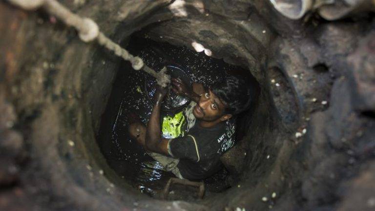 Man in india cleaning sewer drains