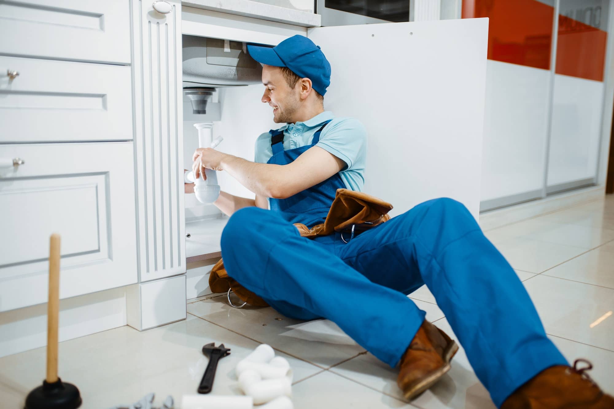 Smiling male plumber in uniform holds drain pipe